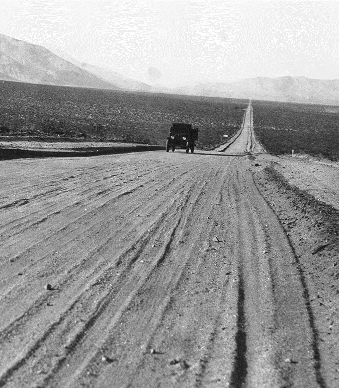 Early 1900s model vehicle driving on dirt road through Eastern Sierra.